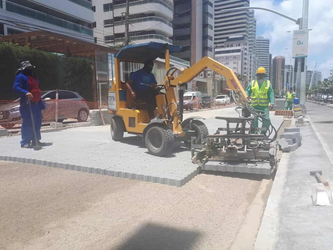 avenida beira mar com operários da construção civil e um trator